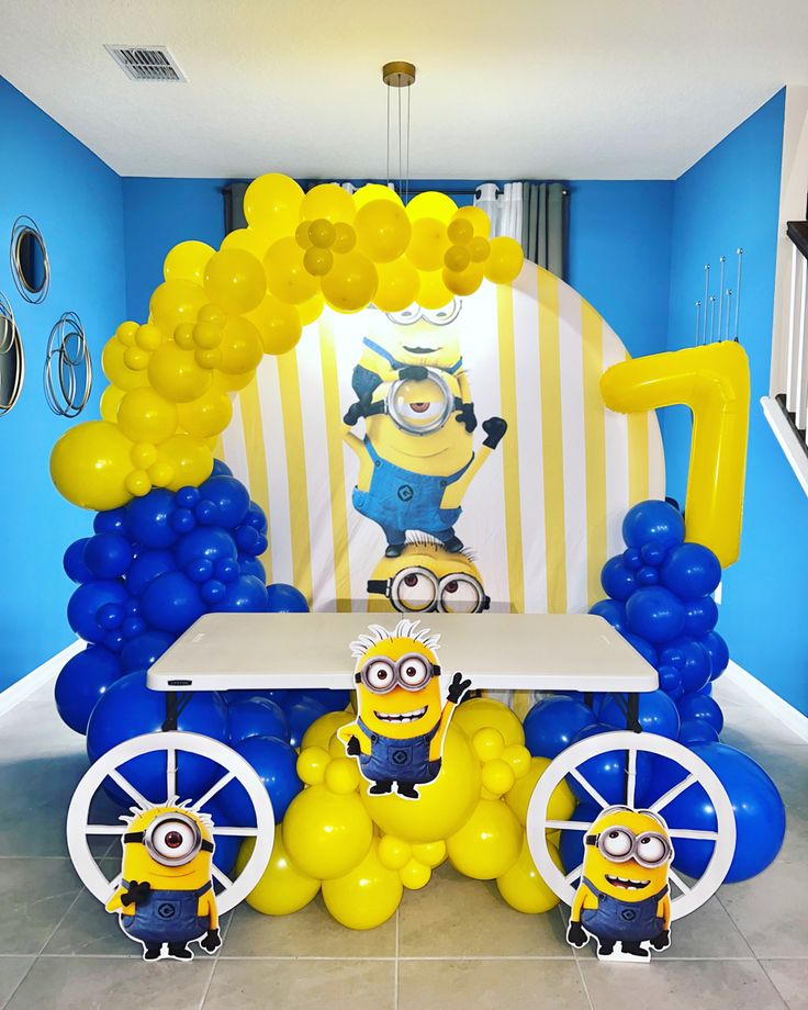 a table topped with balloons and minion decorations