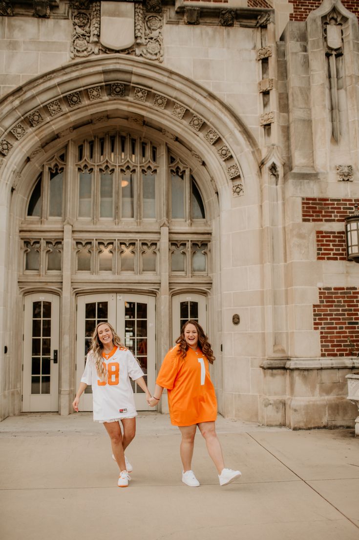 two girls in orange and white dresses are walking towards the front door of an old building