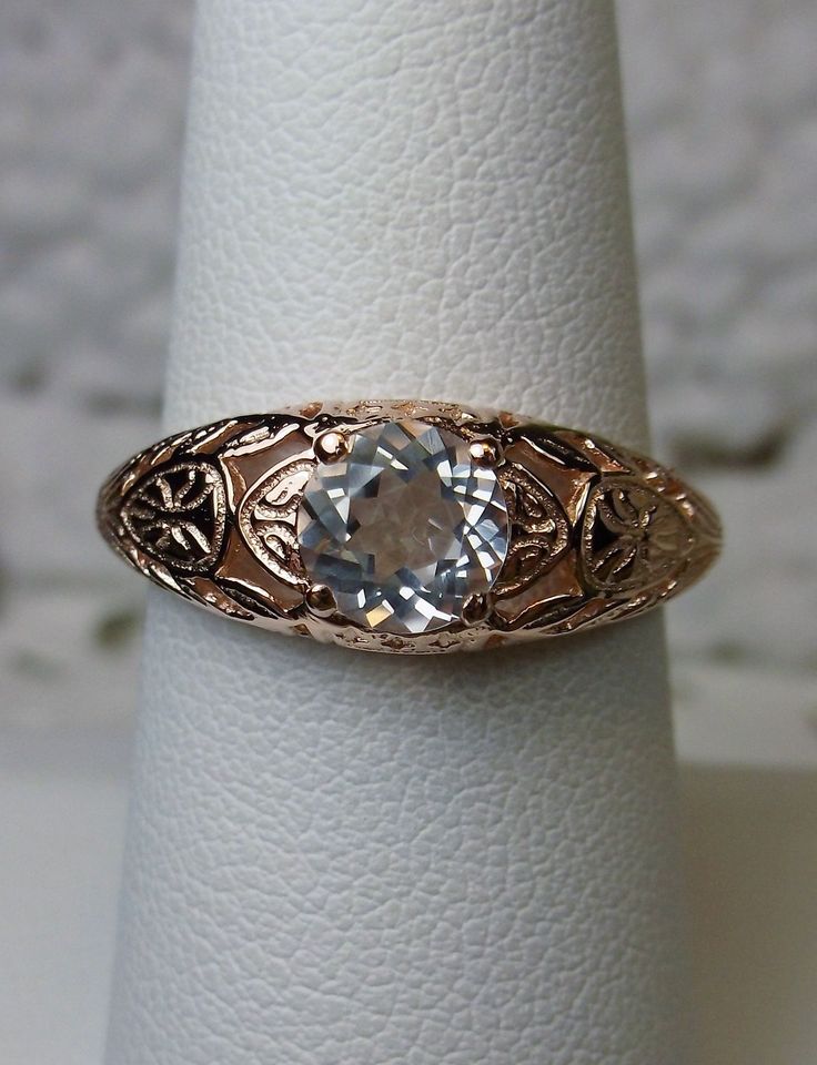 Natural White Topaz Ring Description Etched Wedding Design#160 Custom Here we have a Victorian/Edwardian reproduction ring in 14k rose gold with a stunning natural white topaz gemstone. This full cut round cut .81ct genuine white topaz is 6mm in diameter. The inside of the band is marked 14k for gold. Notice the beautiful floral design of the gold filigree setting. This is a lovely rendition of an Antique filigree wedding ring, and it is made ready to wear. A gift ring box is included and all ri Heirloom Solitaire Topaz Ring For Formal Occasions, Vintage Blue Topaz Ring With Prong Setting, Heirloom Solitaire Topaz Anniversary Ring, Gold Topaz Ring With Intricate Design For Anniversary, Heirloom Topaz Ring With Prong Setting For Anniversary, Classic 14k Gold Topaz Ring For Wedding, Vintage Solitaire Topaz Ring For Wedding, Heirloom Blue Topaz Ring With Diamond Cut, Vintage Solitaire Topaz Wedding Ring