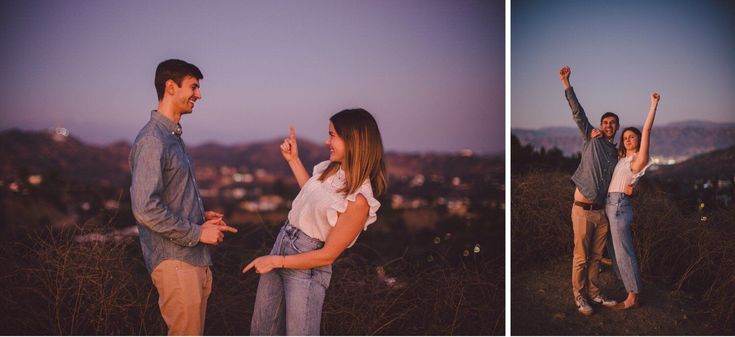 two people standing on top of a hill with their arms in the air and one person holding his hands up