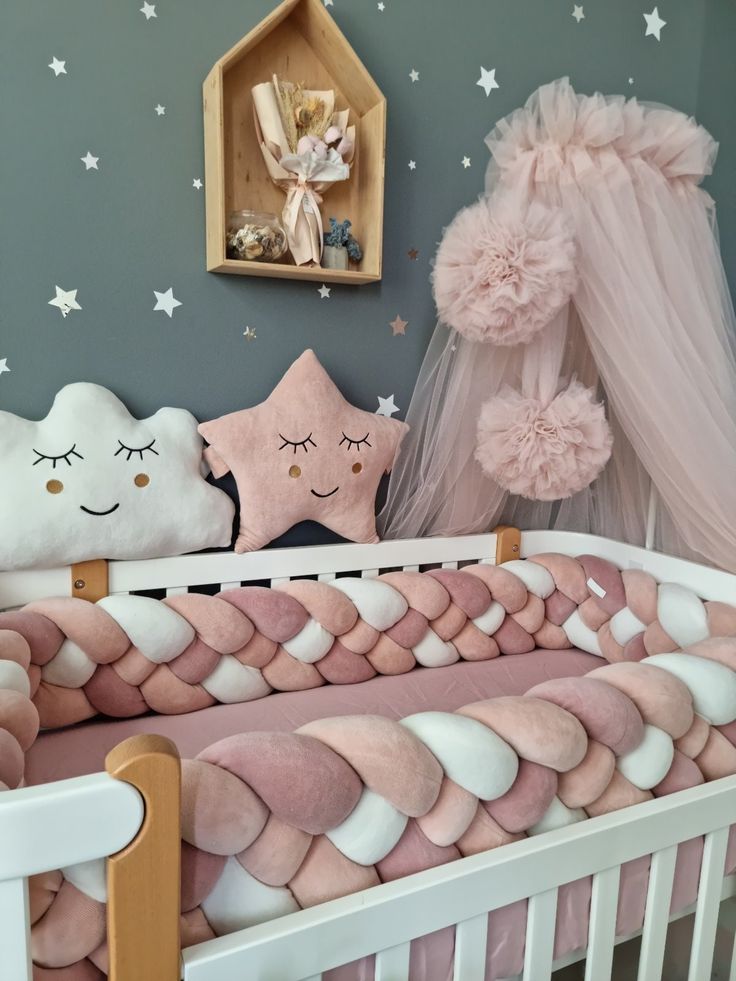 a pink and white baby crib in a room with stars on the wall above it