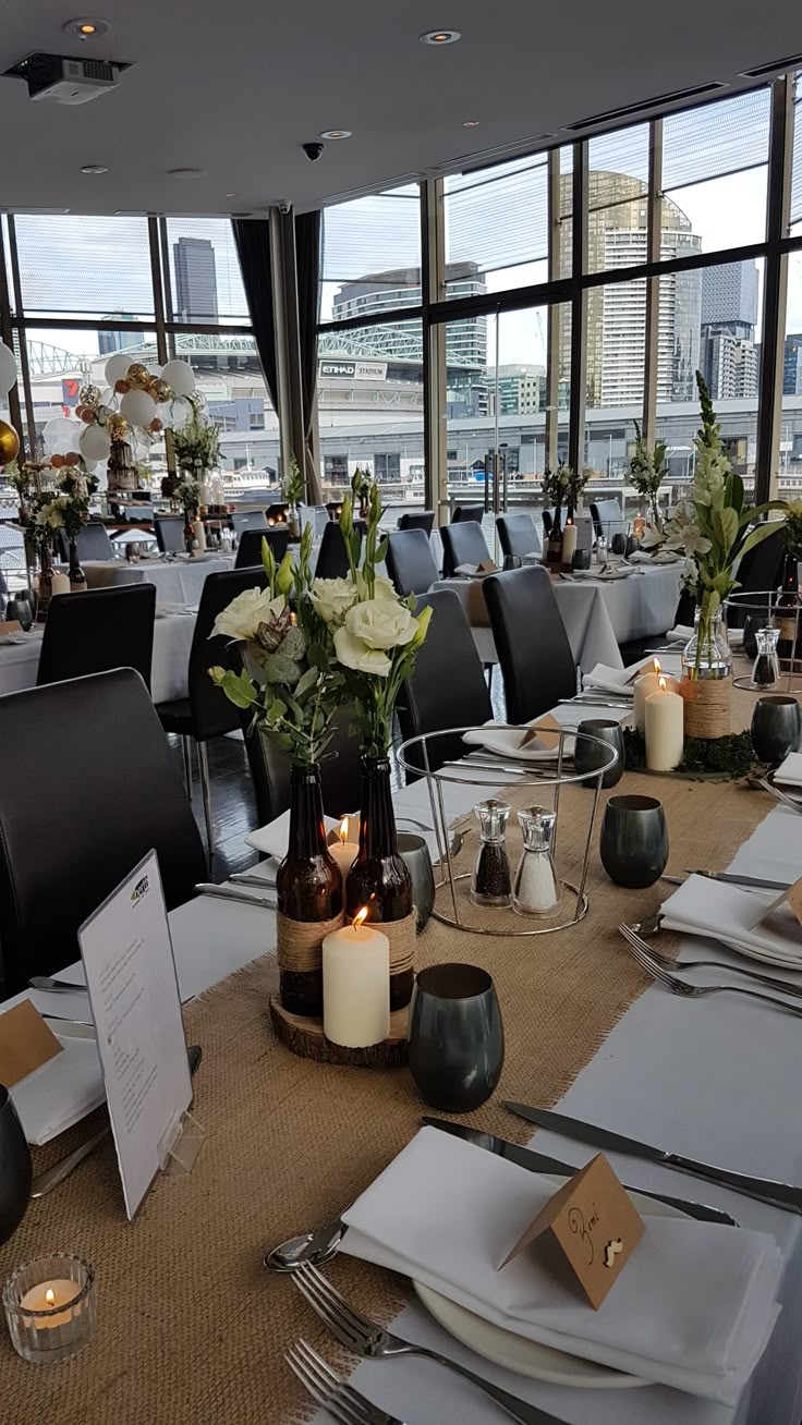 a table set up with place settings and flowers in vases on the tables for an event