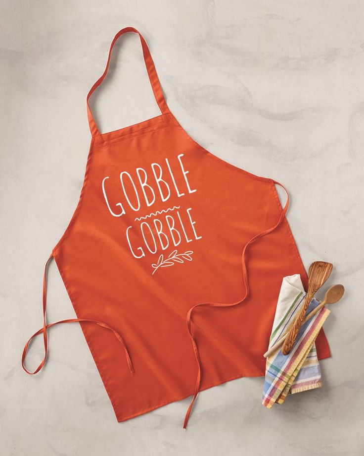 an orange apron with the words gobble gobble on it next to some utensils