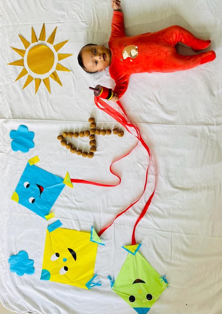 a baby doll laying on top of a bed next to kites and other toys