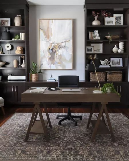 a desk with a laptop on it in front of some bookshelves