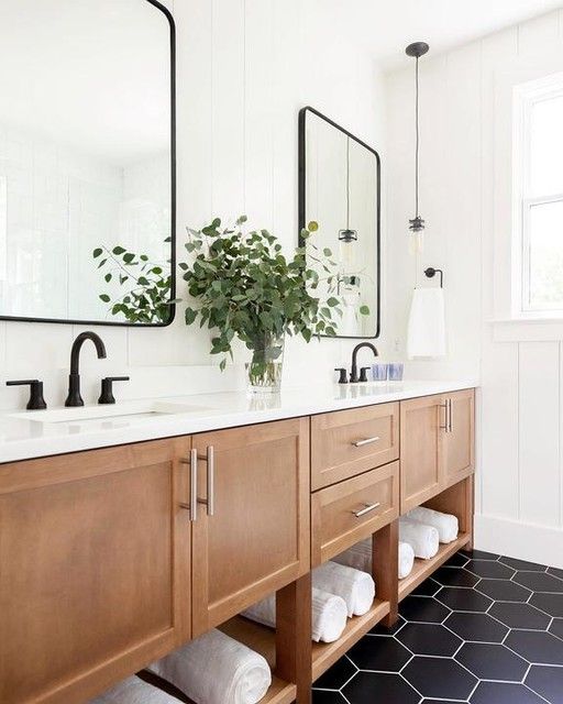 a bathroom with two sinks, mirrors and plants in the vase on the counter top