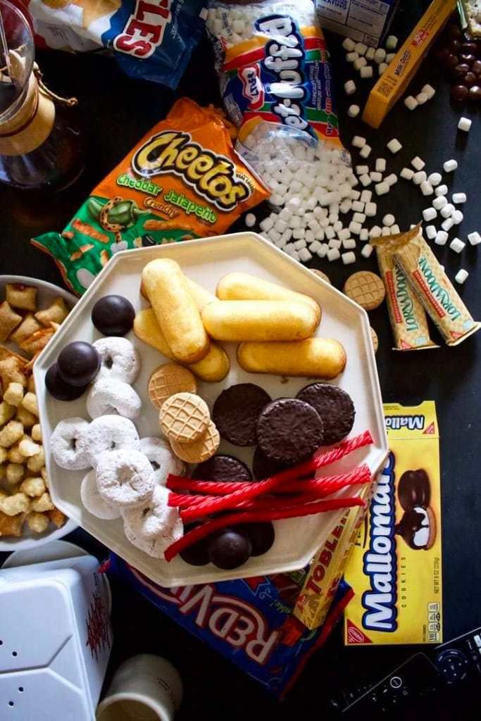 an assortment of snacks on a plate next to candy bars and candies, including marshmallows