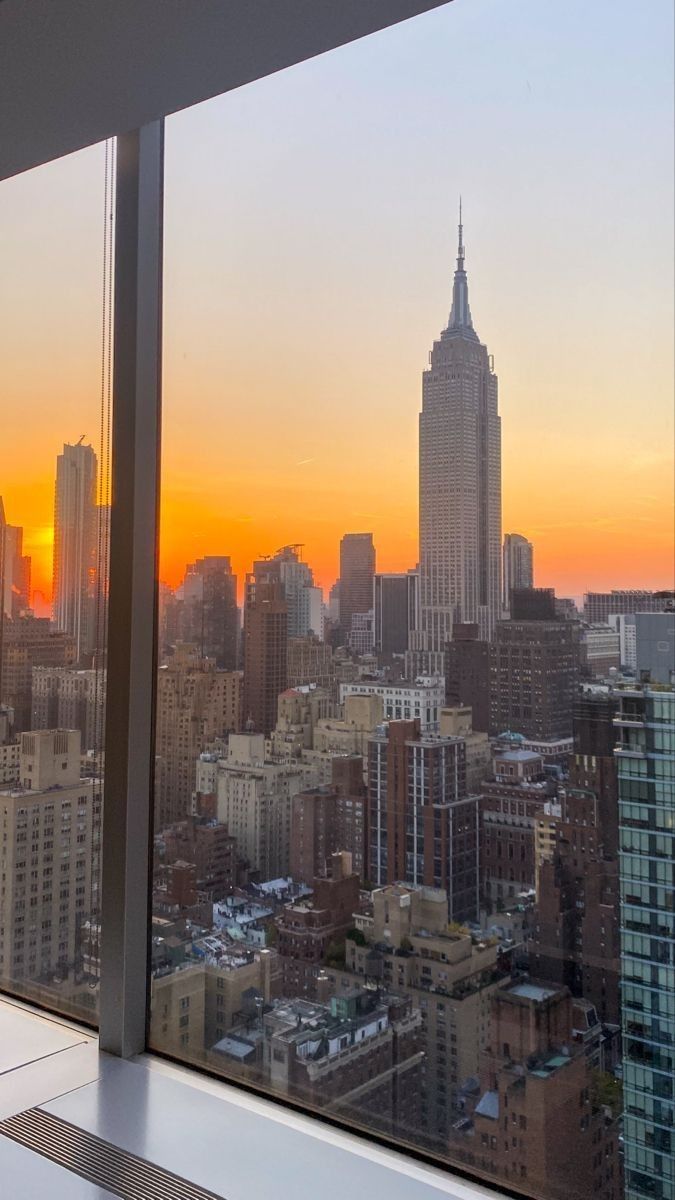 the sun is setting over new york city as seen from an office building's window