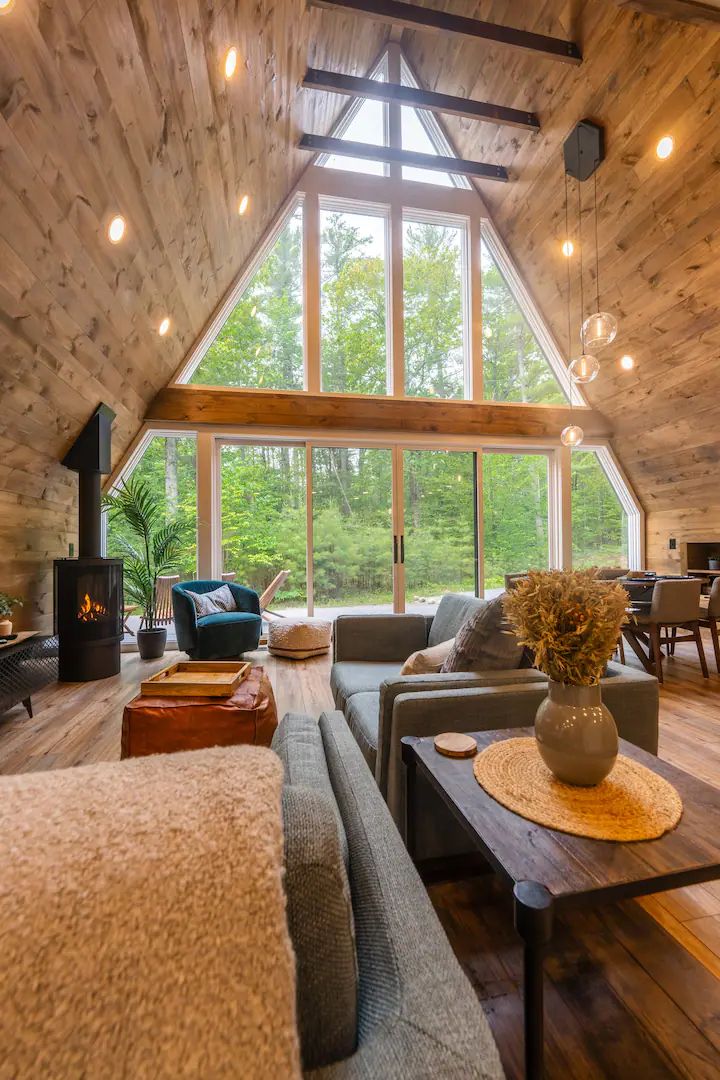 a living room filled with furniture and a fire place next to a wooden wall covered in windows