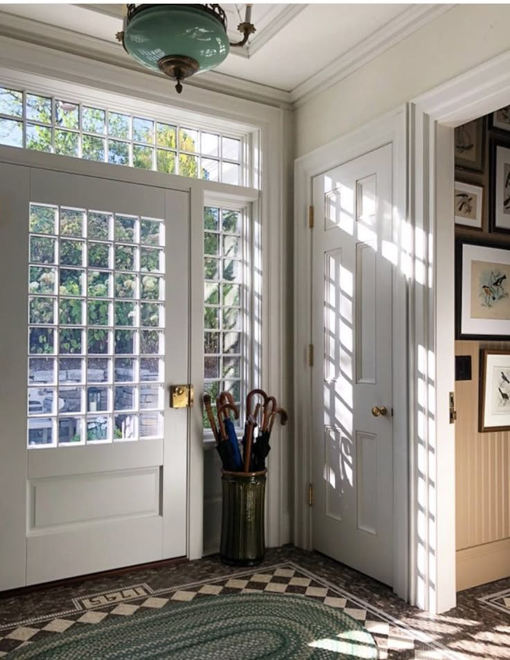 the sun shines through the windows in this entryway to another room with an umbrella and other items