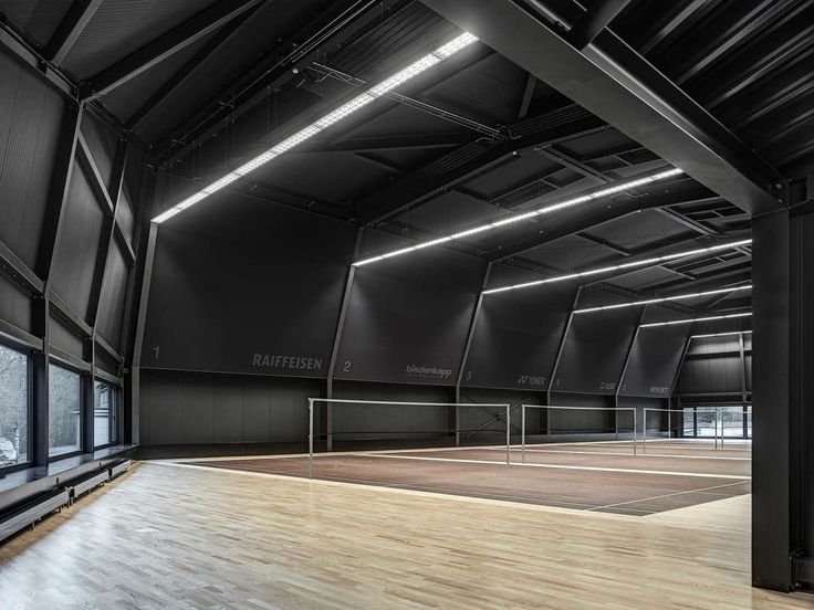 an empty tennis court with lights on the ceiling and hard wood flooring in front of it