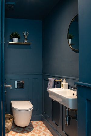 a bathroom with blue walls and tile flooring, toilet and sink in the corner