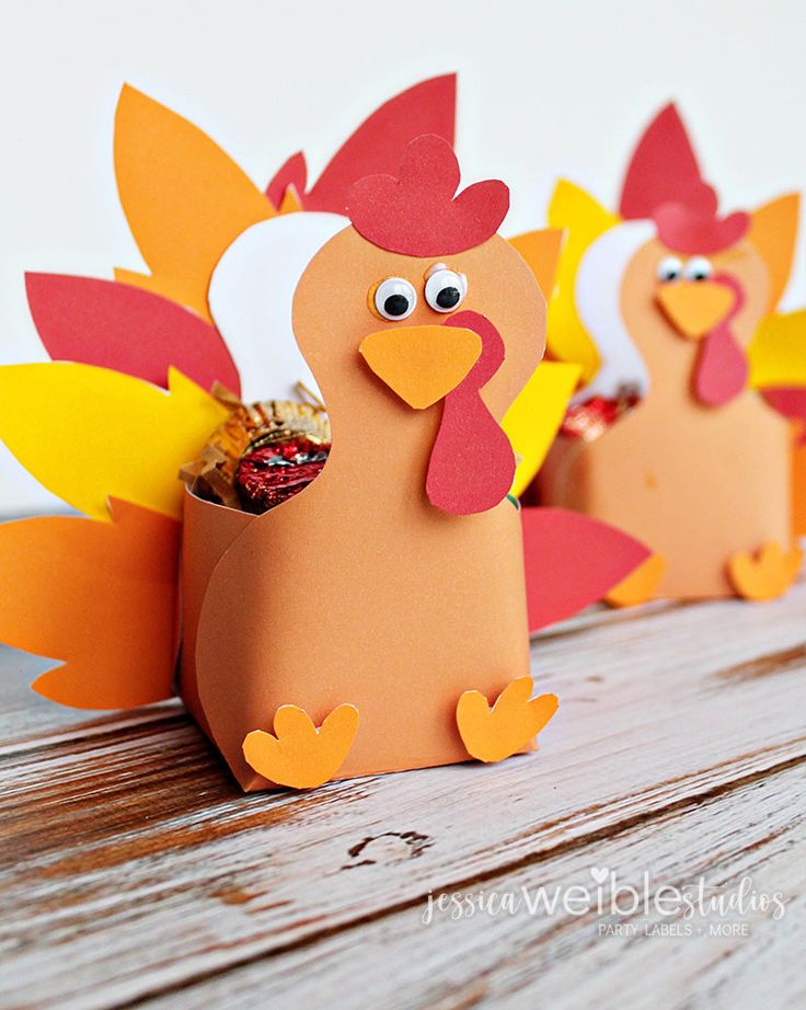 three paper turkeys sitting on top of a wooden table