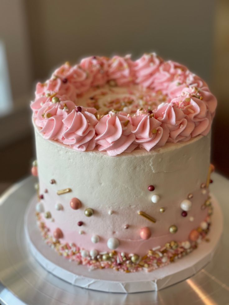 a cake with pink frosting and sprinkles on it sitting on a plate