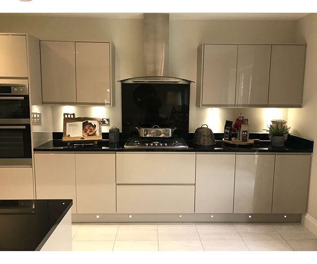 a kitchen with white cabinets and black counter tops is lit up by recessed lighting