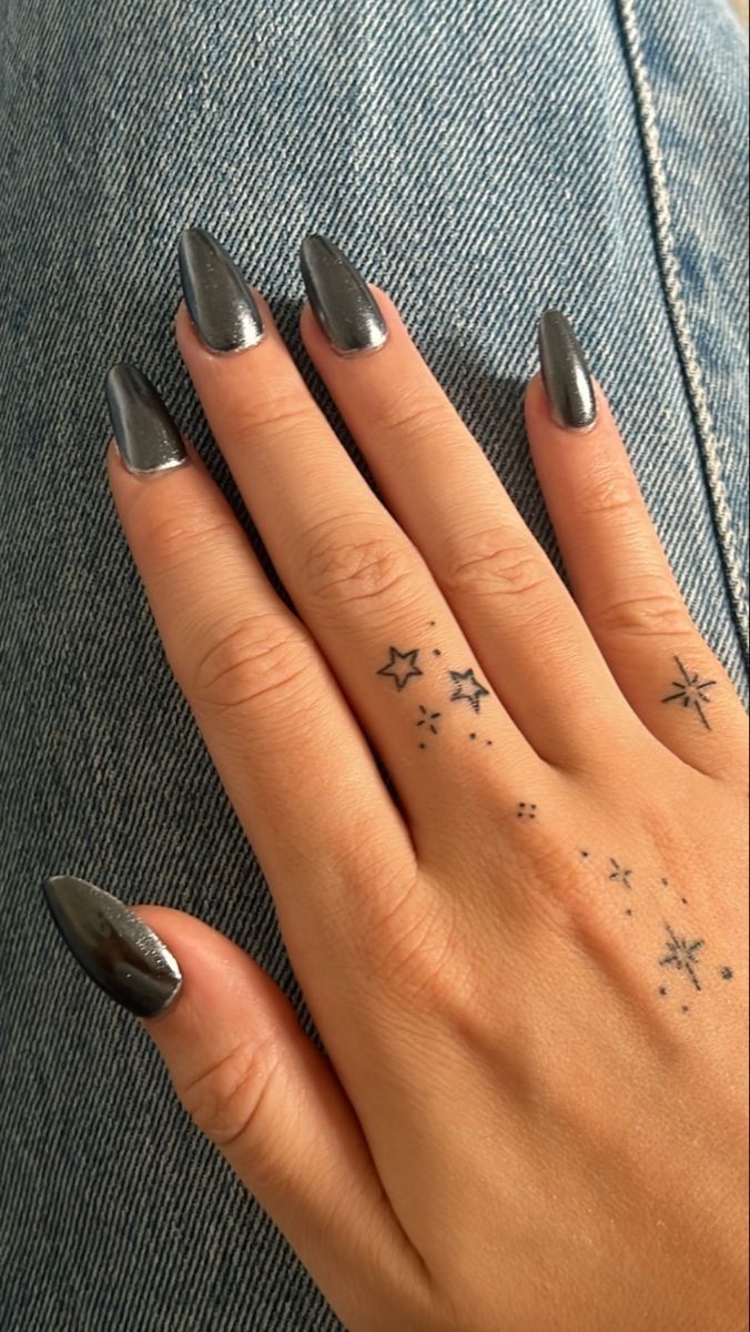 a woman's hand with silver nail polish and stars on her finger, while sitting down