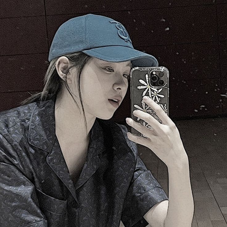 a woman is taking a selfie in front of her cell phone while wearing a baseball cap