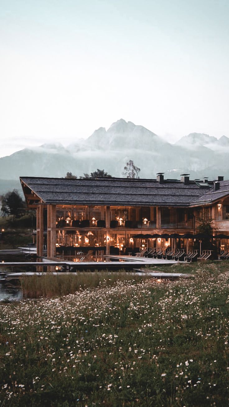 a large wooden building sitting on top of a lush green field next to a lake