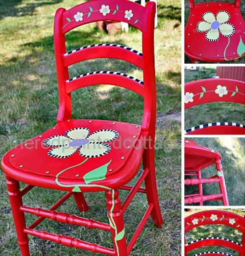 red chair with flowers painted on the back and sides, sitting in grass next to a dog