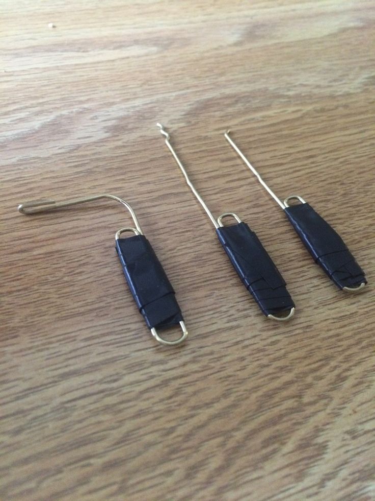 three pairs of scissors sitting on top of a wooden table next to a pair of hooks