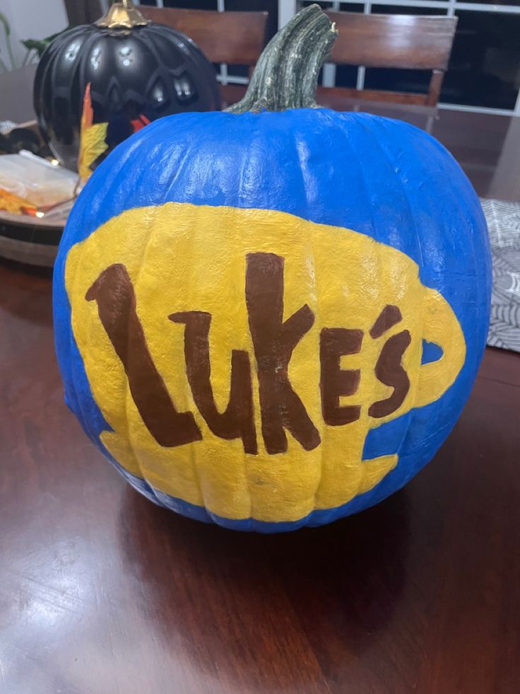 a blue pumpkin with the word luke's painted on it sitting on a table