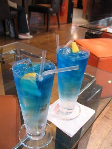 two blue drinks sitting on top of a glass table