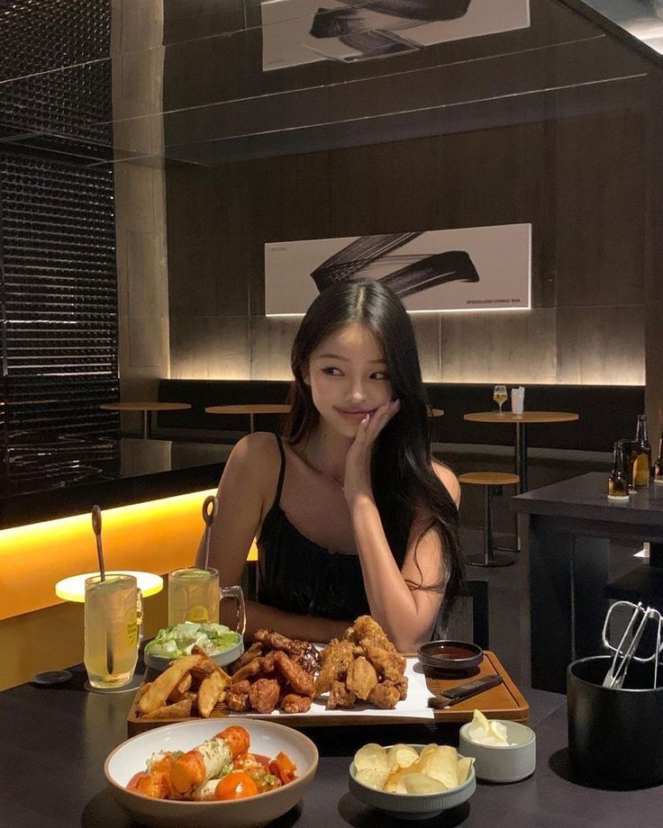 a woman sitting at a table with plates of food