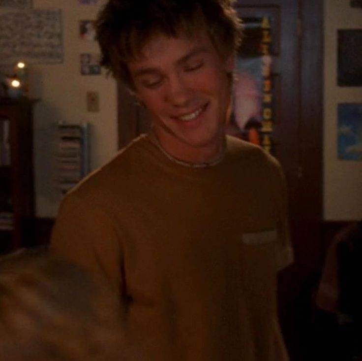 a young man smiles as he looks at his cell phone