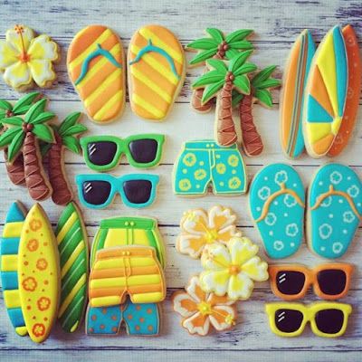 cookies decorated like beach scenes are displayed on a wooden table with sunglasses, surfboards and palm trees