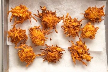 several pieces of fried food sitting on top of a white paper covered baking sheet in a pan