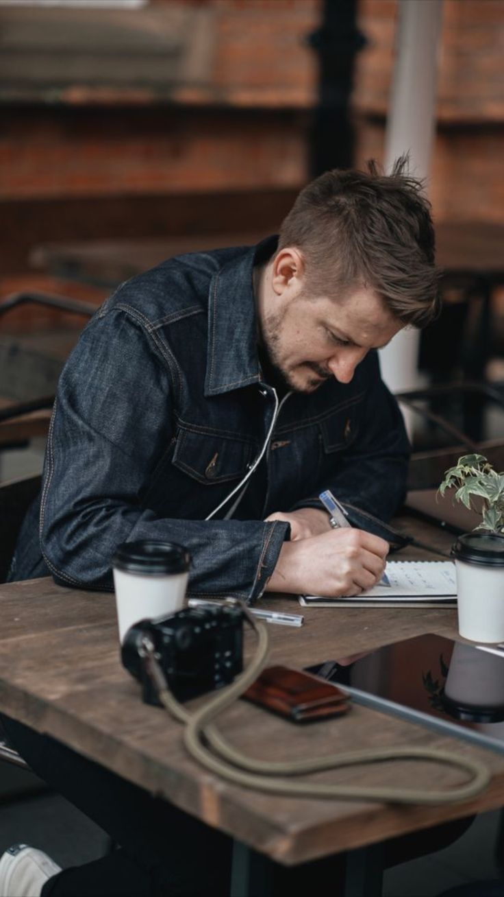 a man sitting at a table writing on a piece of paper