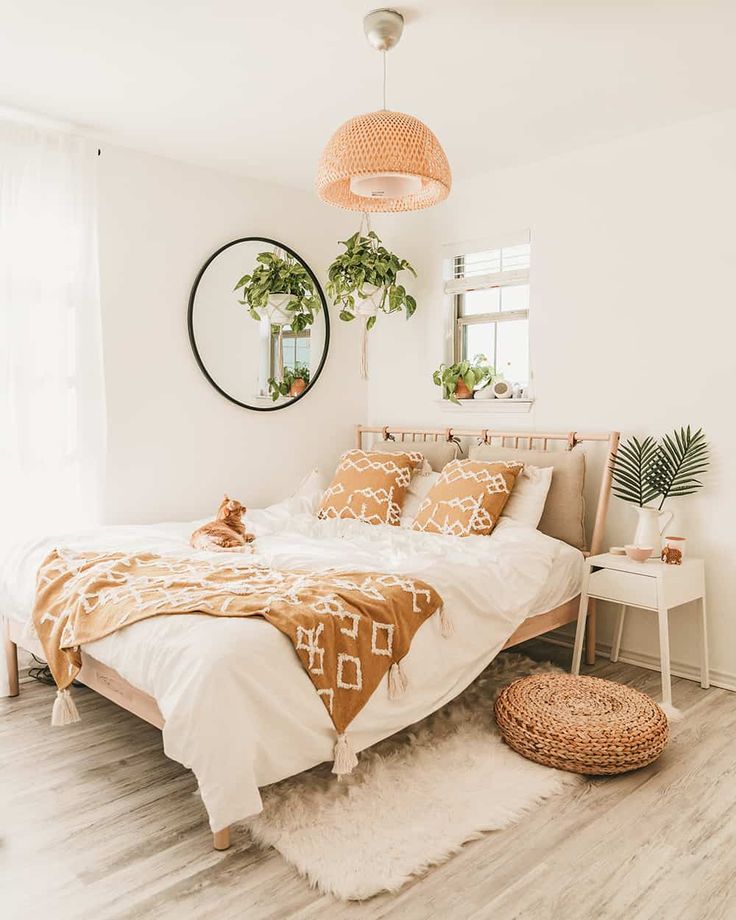 a bedroom with white walls and wooden flooring is decorated in neutral colors, including an orange bed spread