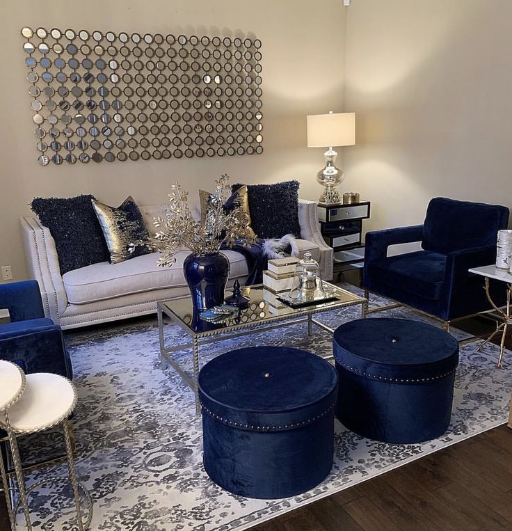 a living room with blue velvet furniture and mirrors on the wall above it's windows