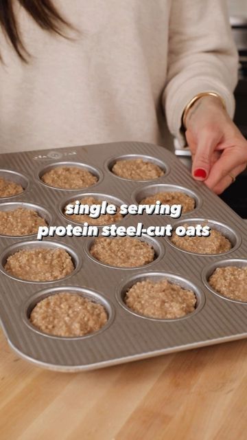 a woman holding a muffin pan filled with oatmeal in front of her