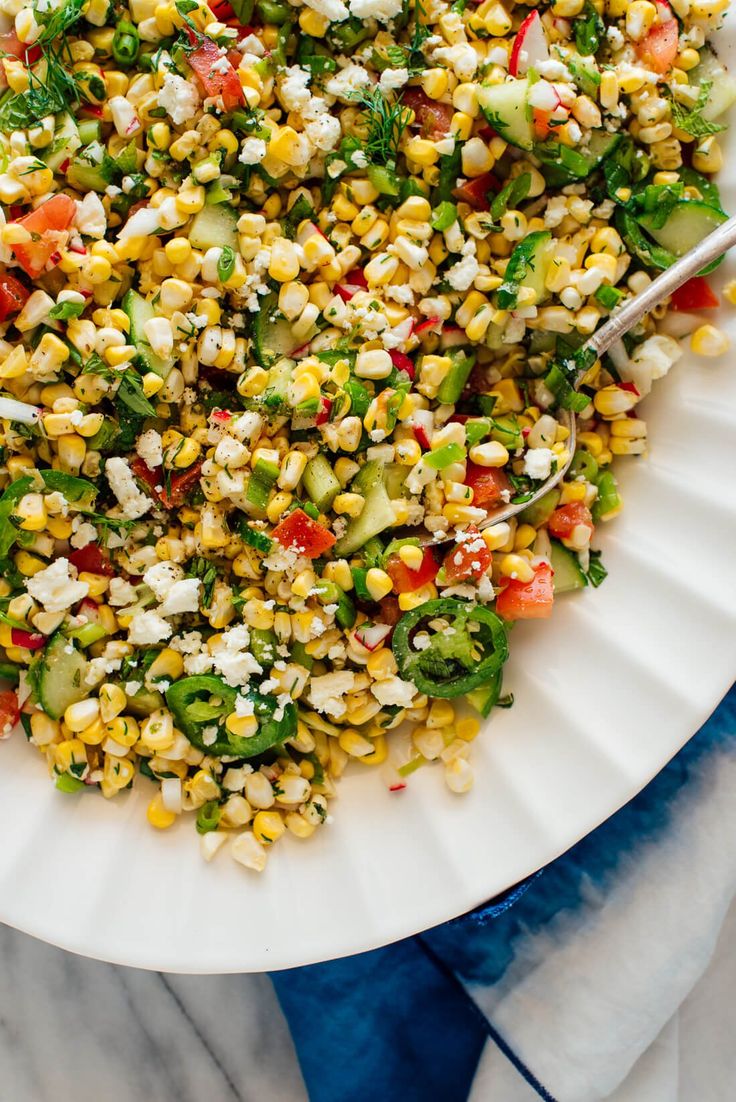 a white plate topped with corn salad on top of a table