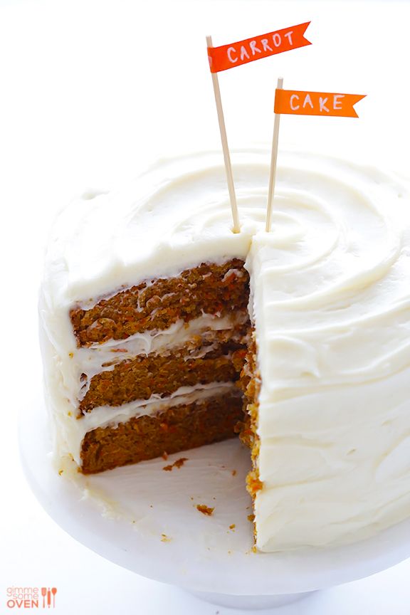 a carrot cake with white frosting and two orange flags sticking out of the top