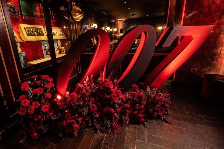 the number twenty seven is surrounded by flowers in front of a wall with red lights