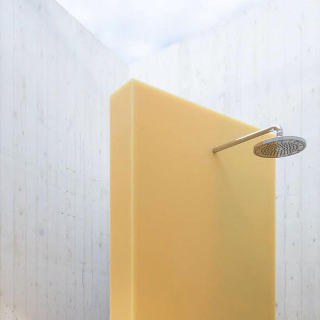 a yellow shower head in the corner of a bathroom