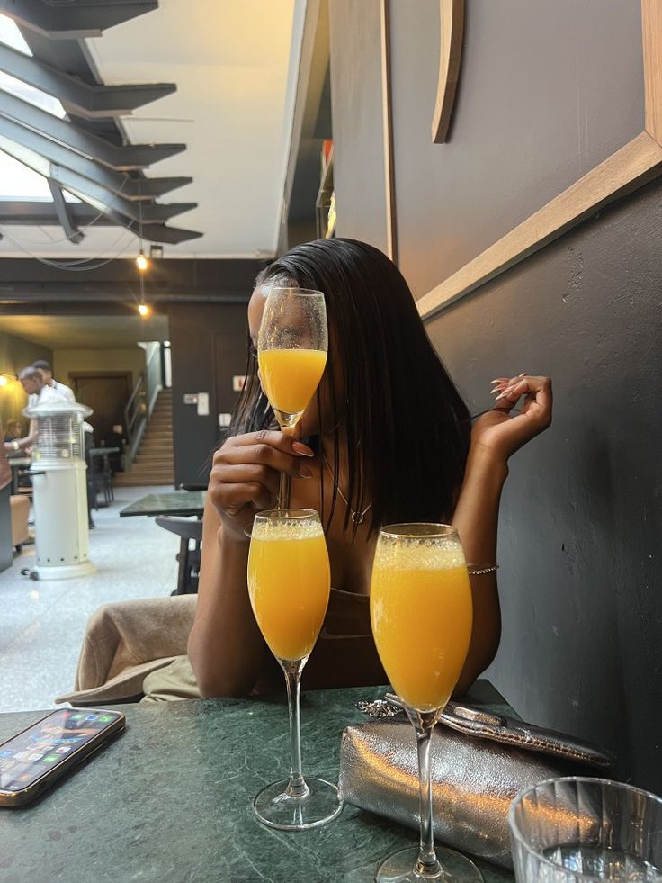 a woman sitting at a table with two glasses of orange juice