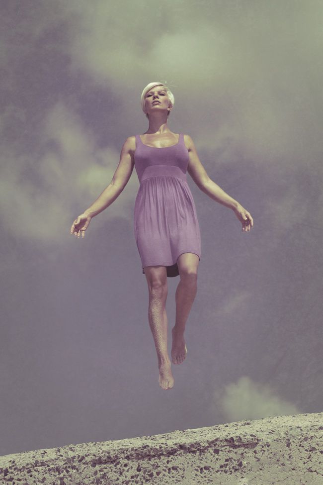 a woman flying through the air while wearing a purple dress