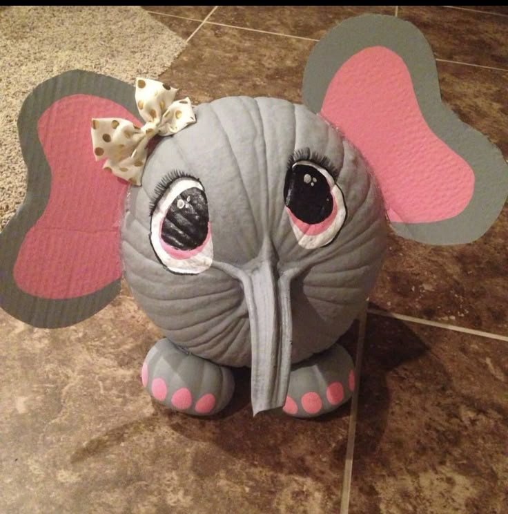 an elephant toy sitting on top of a tiled floor next to a tile floor with pink and gray accents