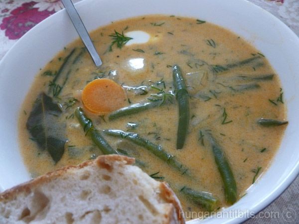 a white bowl filled with soup next to a slice of bread