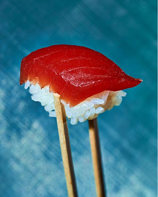 two sushi sticks with chopsticks sticking out of them on a blue background