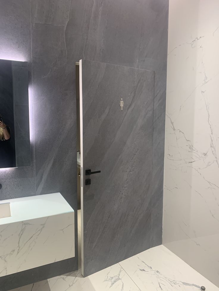 a modern bathroom with marble walls and flooring, along with a white countertop