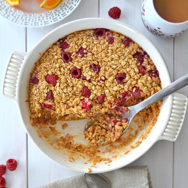 a white bowl filled with granola next to a cup of coffee and orange slices