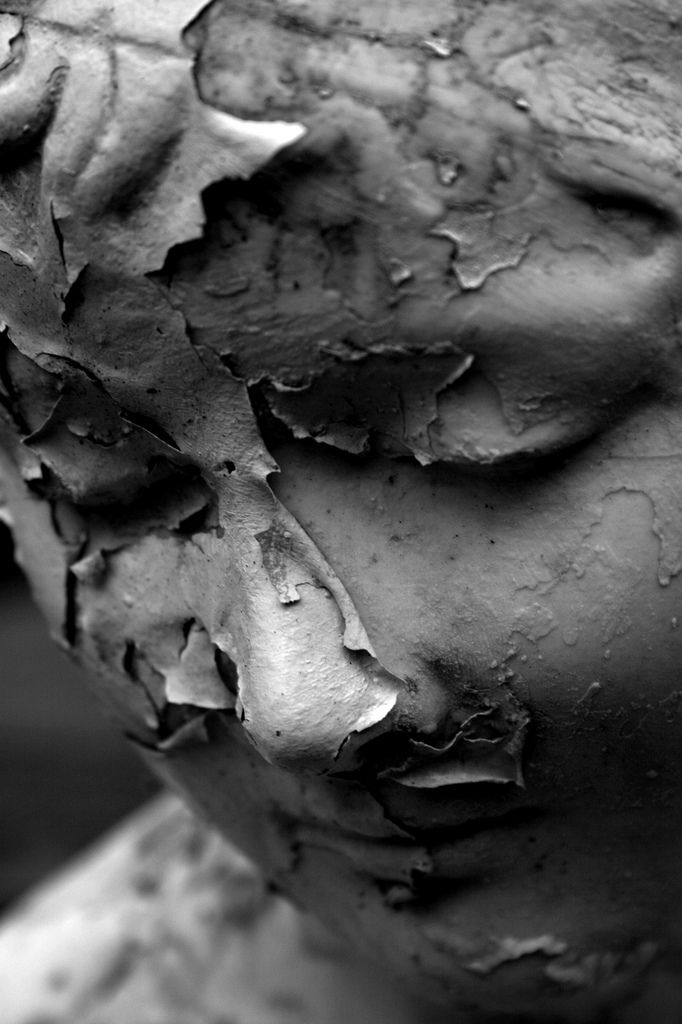 a black and white photo of a statue with peeling paint on it's face