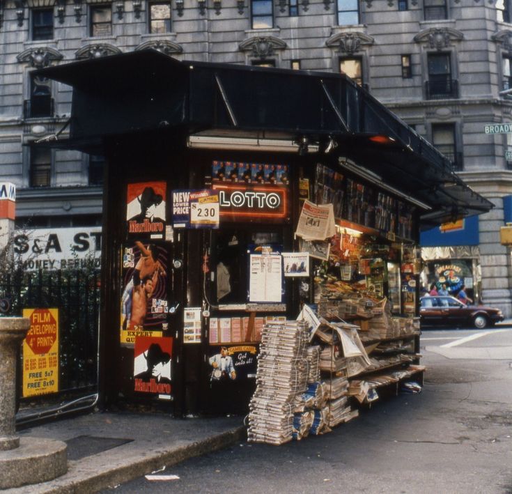 an old photo of a small store on the side of the street in front of a tall building