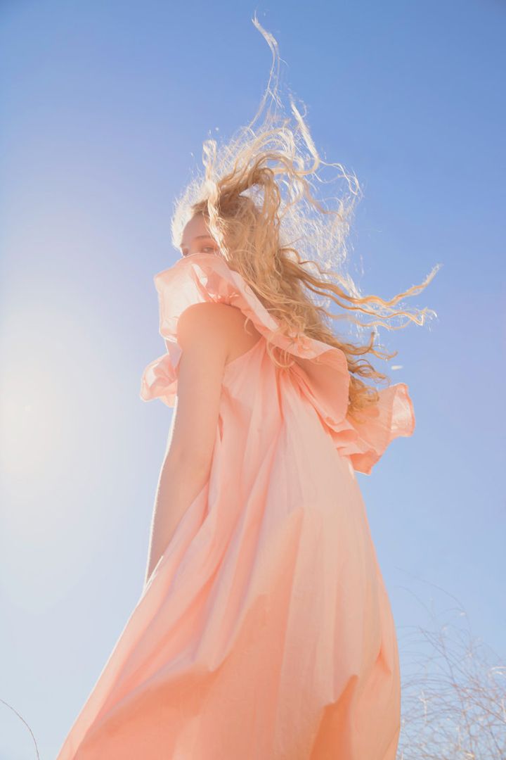 a woman in an orange dress is flying through the air with her hair back to the camera