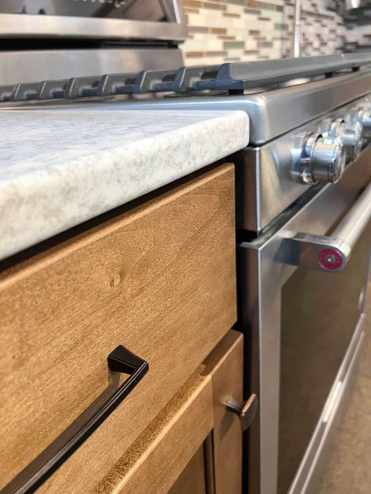 a stainless steel oven with wooden drawers and knobs on the front, in a kitchen