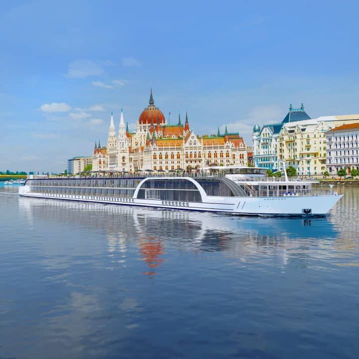 a large white boat floating on top of a river next to tall buildings in the background